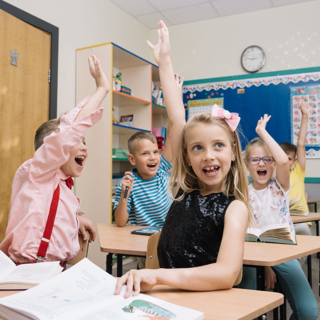 aclamando los ninos de la escuela en la clase levantando las manos